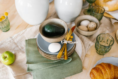 Easter festive spring table setting decoration, green napkins, eggs, avocado in a plate