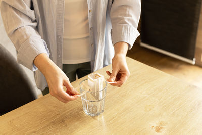 Young woman unpacks a bag of filter coffee and puts it in a glass, hand view