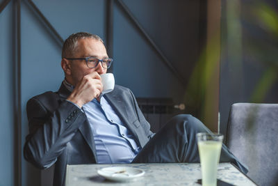 Thoughtful businessman drinking coffee while sitting at restaurant