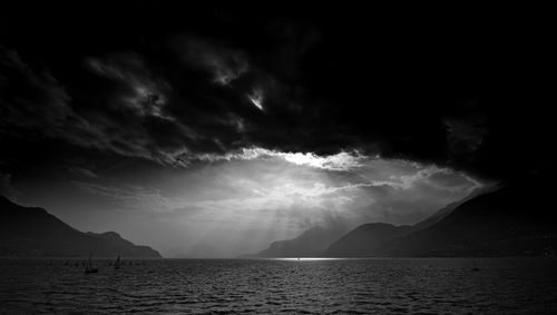 Scenic view of sea and mountains against storm clouds