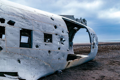 Crashed airplane on barren field against sky