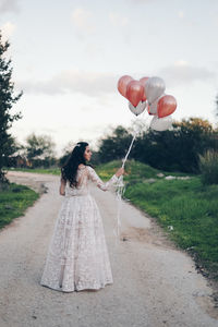 Rear view of woman with umbrella standing on road