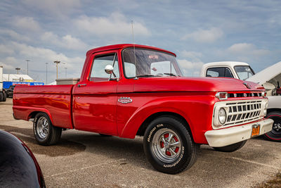 Side view of red vintage car against cloudy sky