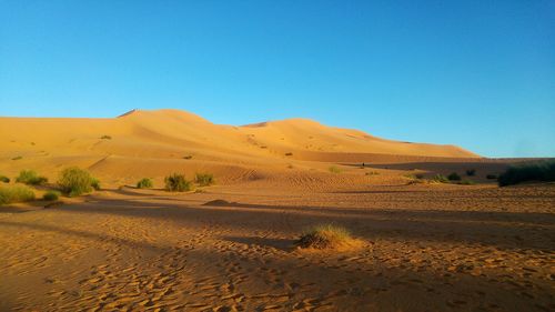 Scenic view of desert against clear blue sky