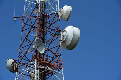 Low angle view of communications tower against clear blue sky