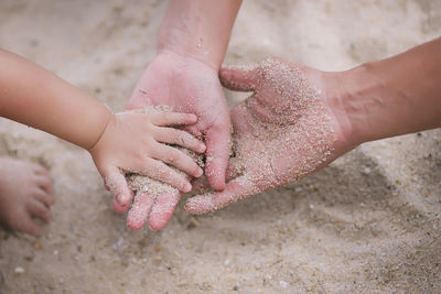 Cropped hands of family playing with sand at beach