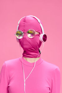 Woman wearing mask against pink background