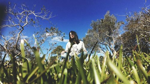 Low angle view of woman standing against clear blue sky