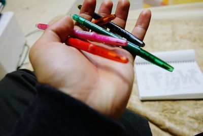 Close-up of human hand holding colorful pens