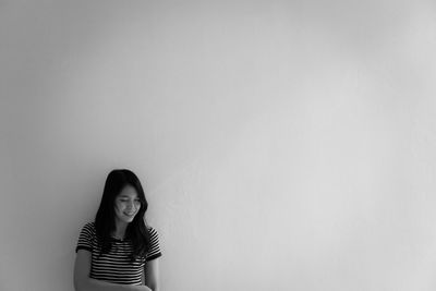 Portrait of a young woman standing against wall