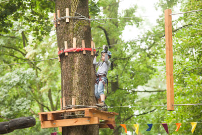 Man climbing on rope against trees