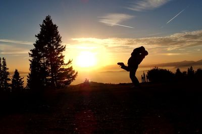 Silhouette couple kissing on field against sky during sunset