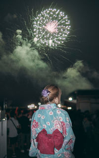 Rear view of woman with umbrella standing at night