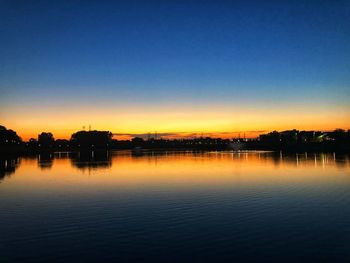 Scenic view of lake against clear sky at sunset