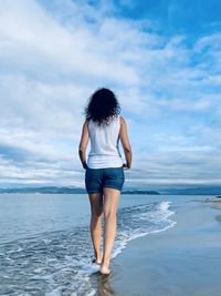 Rear view of woman walking along the coast
