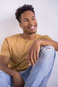 Smiling young man sitting against white background