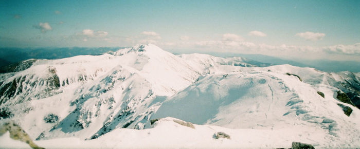 Scenic view of snow covered mountains against blue sky