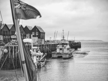 Boats moored at harbor against sky