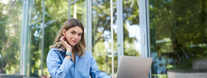 Young woman looking away while standing outdoors