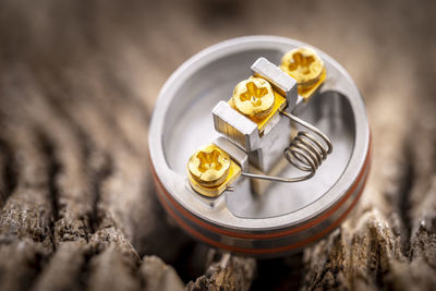 Single space coil in rebuildable dripping atomizer on rustic wood texture background, vaping device