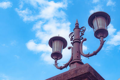 Low angle view of street light by building against sky