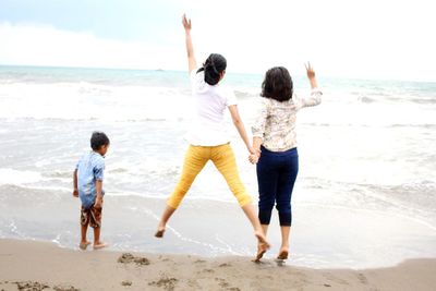 Rear view of friends enjoying on beach