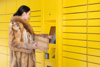 Portrait of woman standing against yellow wall