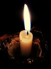 Close-up of lit candle against black background