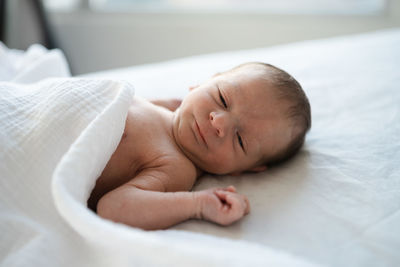 Close-up of baby lying on bed at home