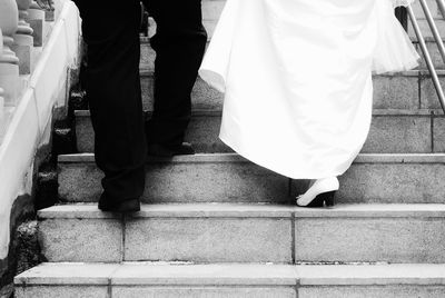 Low section of bride and groom walking on steps