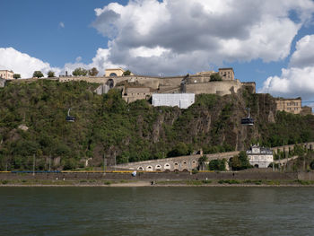 Buildings at waterfront against cloudy sky