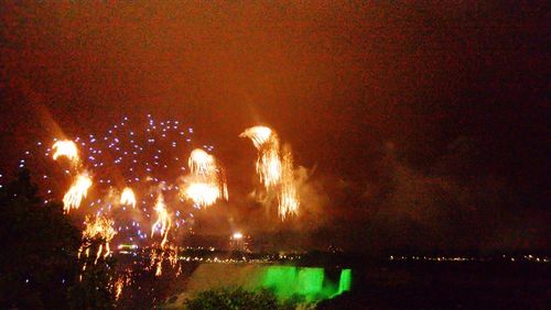 Firework display on field against sky at night