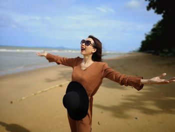 Woman with arms outstretched standing at beach