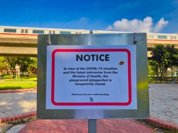 Close-up of information sign against blue sky