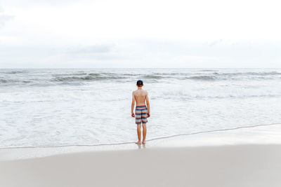 Full length rear view of shirtless man on beach