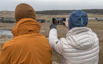 Rear view of man photographing woman using smart phone