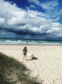 High angle view of girl walking with dog at beach