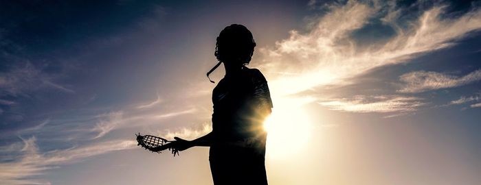 Silhouette sportsman standing against sky during sunset