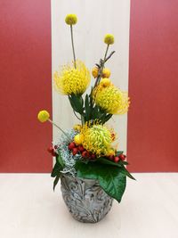 Close-up of flower vase on table against wall