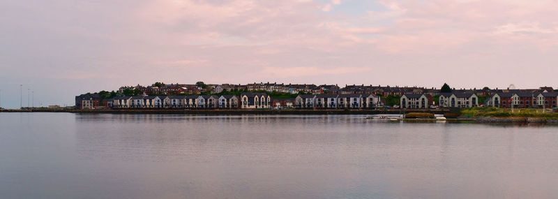 Scenic view of river by buildings against sky