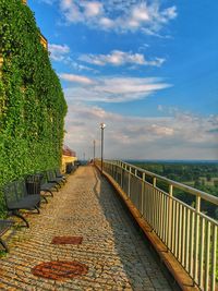 Footpath by railing against sky