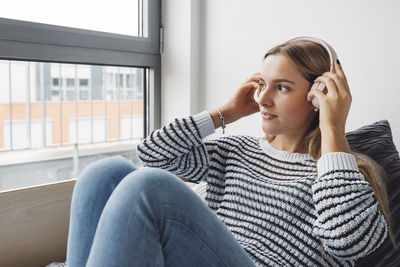 Young woman using mobile phone while sitting on sofa at home