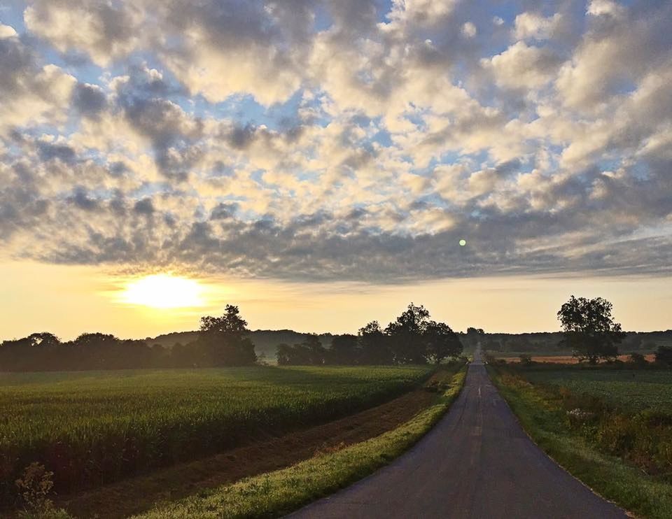 ROAD AMIDST FIELD AGAINST SKY AT SUNSET