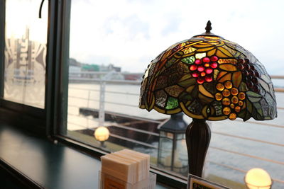 Close-up of electric lamp on table by window in cafe