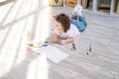 High angle view of girl drawing in book on floor