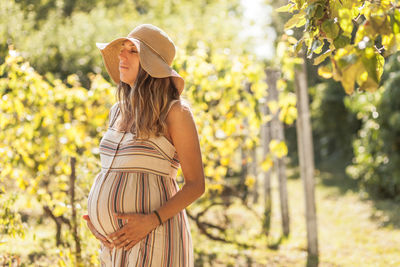 Pregnant woman holding her belly in nature.