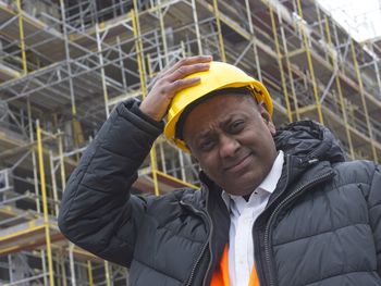 Civil engineer or factory worker fixing his safety helmet and looking frowning at the camera