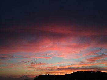 Low angle view of dramatic sky over silhouette landscape