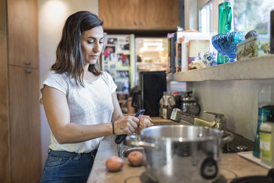 Woman peeling potato at kitchen counter