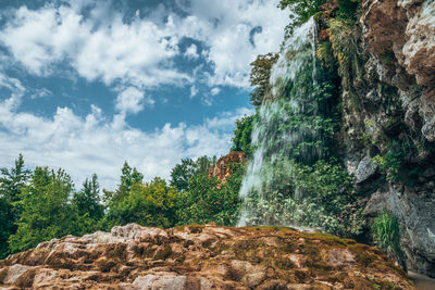 Low angle view of waterfall against sky